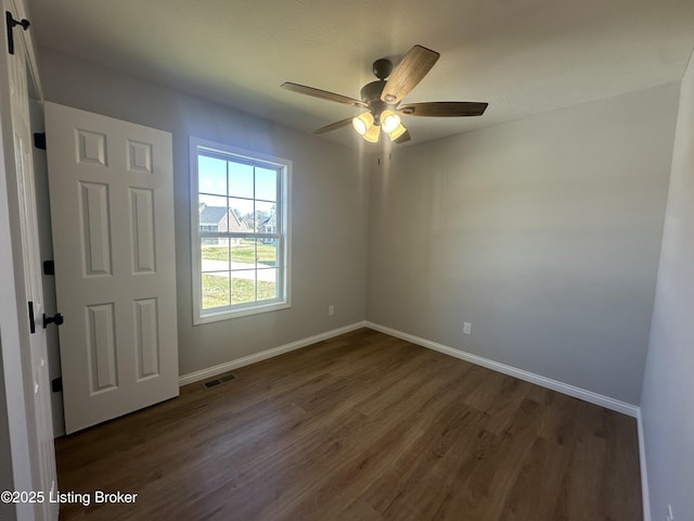 spare room featuring visible vents, baseboards, dark wood-type flooring, and a ceiling fan