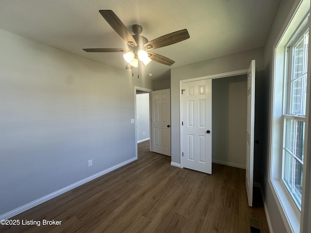 unfurnished bedroom with visible vents, baseboards, ceiling fan, dark wood-type flooring, and a closet