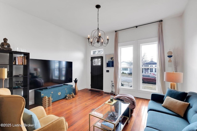 living room with a chandelier, hardwood / wood-style flooring, and baseboards