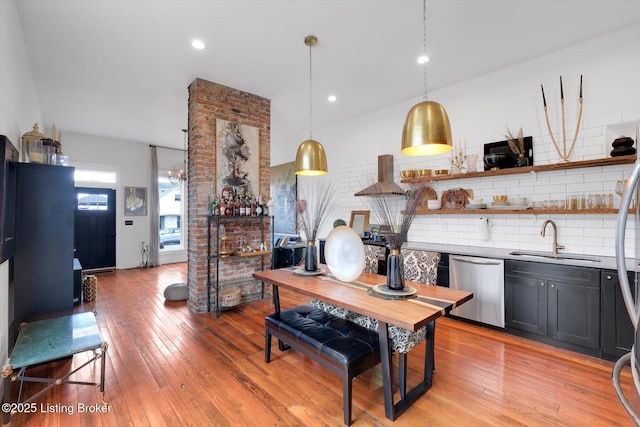 kitchen with stainless steel dishwasher, light wood-type flooring, a sink, and tasteful backsplash