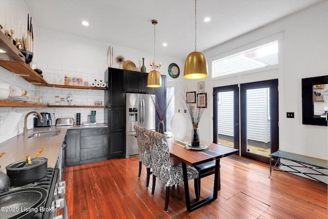 kitchen with open shelves, wood-type flooring, stainless steel appliances, and a sink