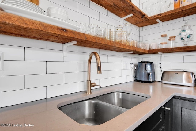 kitchen with light countertops, a sink, decorative backsplash, and open shelves