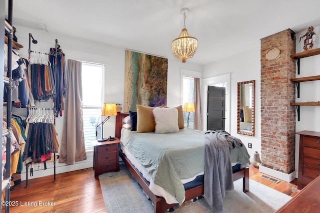 bedroom featuring a chandelier, hardwood / wood-style floors, visible vents, and baseboards