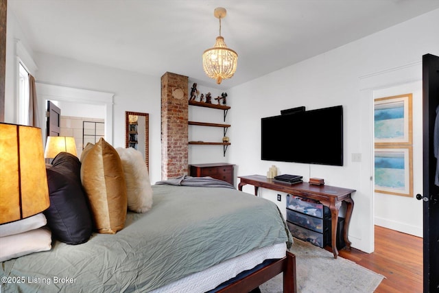 bedroom with a notable chandelier, baseboards, and wood finished floors