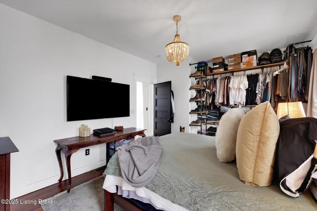 bedroom with baseboards, a chandelier, and wood finished floors