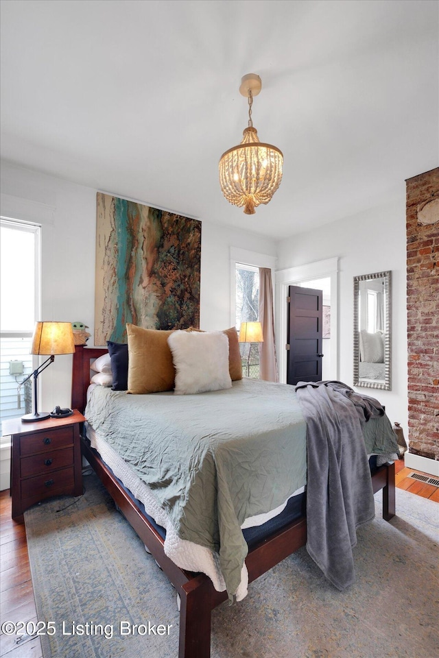 bedroom with visible vents, an inviting chandelier, and wood finished floors