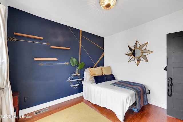 bedroom featuring visible vents, baseboards, and wood finished floors