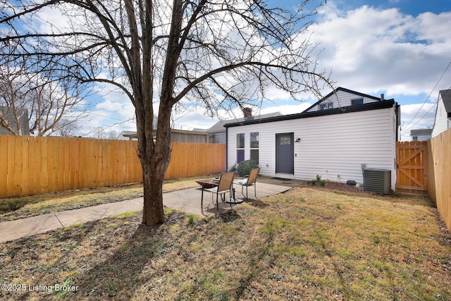 rear view of property featuring central AC, a lawn, a patio area, and a fenced backyard