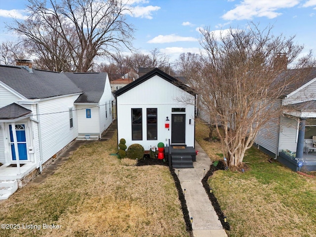 bungalow-style house with entry steps, a shingled roof, and a front yard