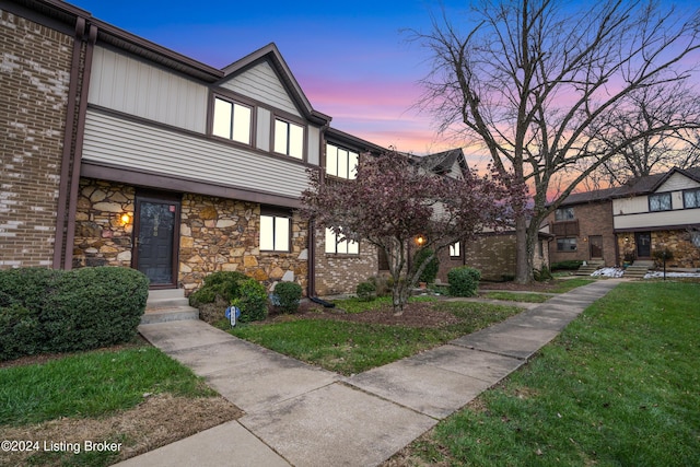 view of property with stone siding and a front lawn