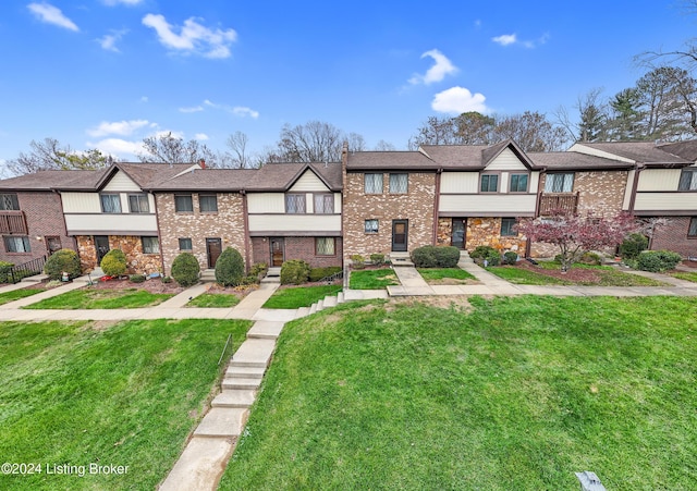 multi unit property with brick siding and a front yard