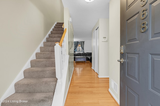 entryway featuring baseboards, visible vents, stairway, and light wood finished floors