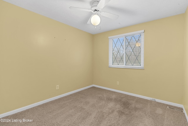 carpeted spare room featuring visible vents, ceiling fan, and baseboards