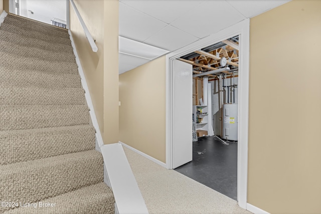 stairway featuring finished concrete floors, electric water heater, and baseboards