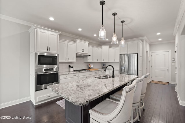 kitchen with stainless steel appliances, backsplash, white cabinetry, a sink, and under cabinet range hood