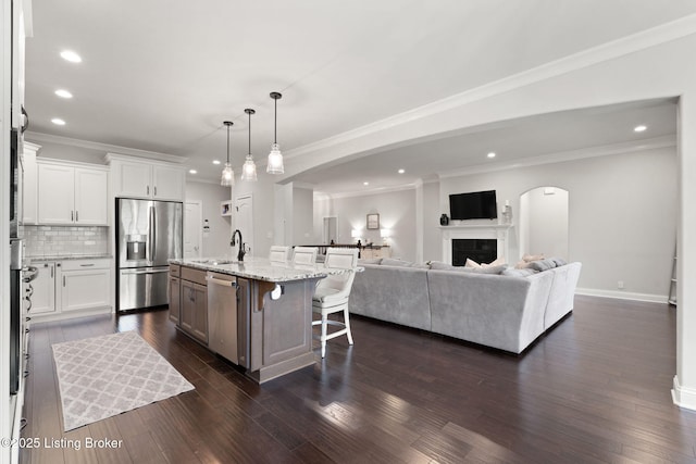 kitchen with stainless steel appliances, a sink, open floor plan, decorative backsplash, and a kitchen bar