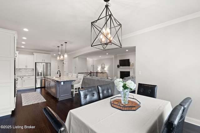 dining room featuring arched walkways, recessed lighting, dark wood-type flooring, a fireplace, and ornamental molding