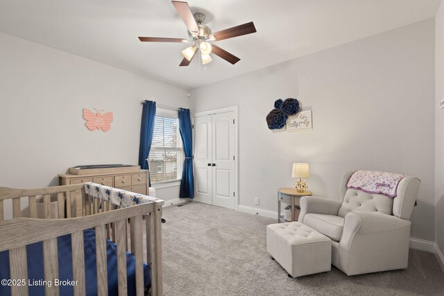 carpeted bedroom featuring a crib, a ceiling fan, baseboards, and a closet