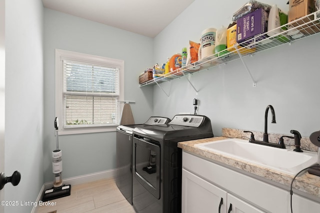 laundry room with independent washer and dryer, cabinet space, a sink, and baseboards