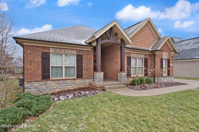 view of front of house with a shingled roof, a front yard, stone siding, and brick siding