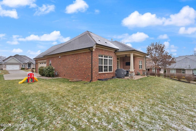 rear view of house with a patio area, brick siding, a yard, and an attached garage