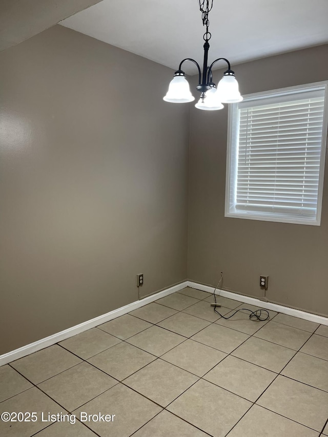 empty room with baseboards, a notable chandelier, and light tile patterned flooring