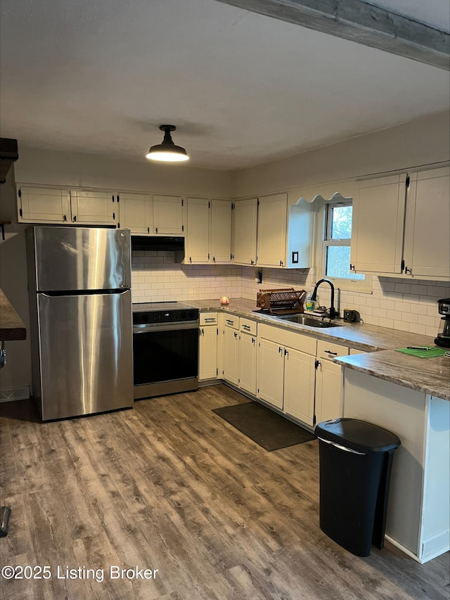 kitchen featuring dark wood-style floors, freestanding refrigerator, white cabinets, electric stove, and under cabinet range hood