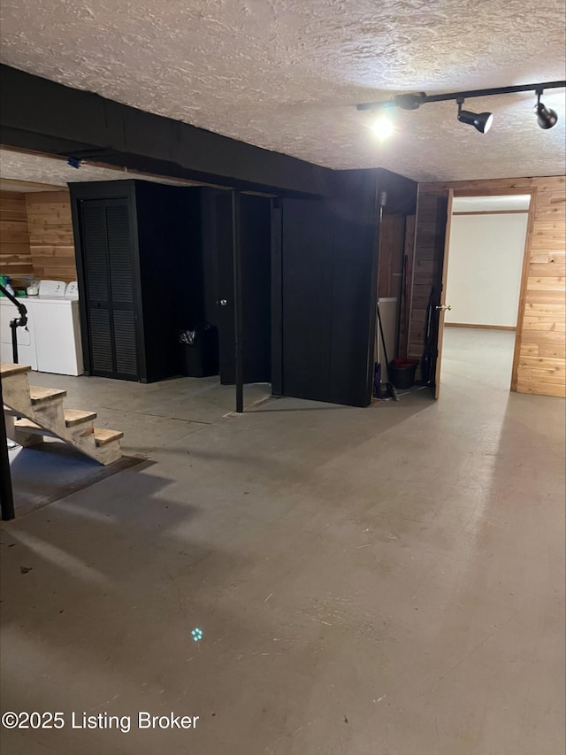 unfinished basement featuring washer and dryer, wooden walls, and a textured ceiling