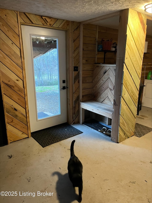 doorway to outside with wooden walls and a textured ceiling