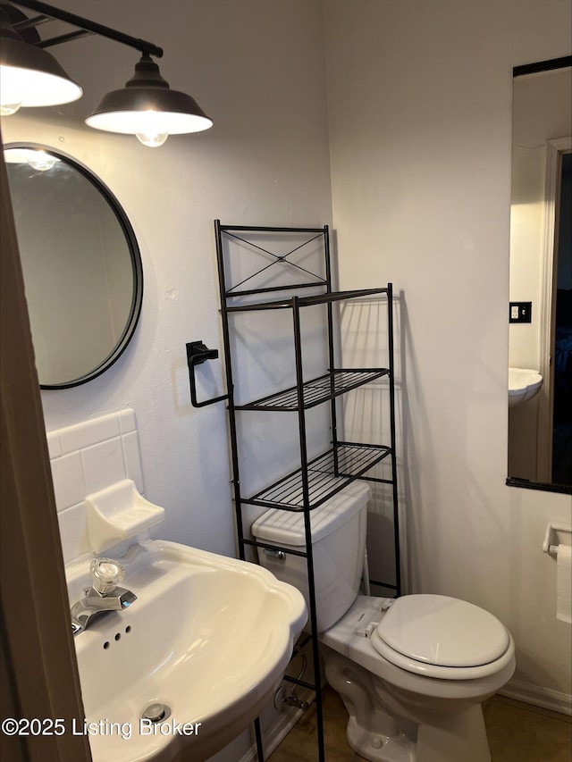 bathroom featuring a sink, backsplash, baseboards, and toilet