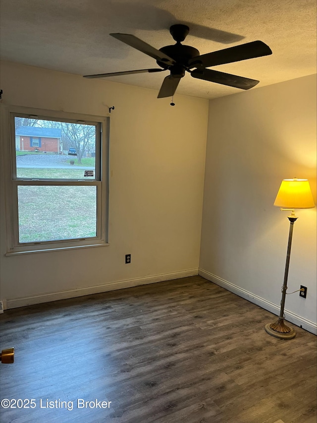 empty room with baseboards, a textured ceiling, and wood finished floors