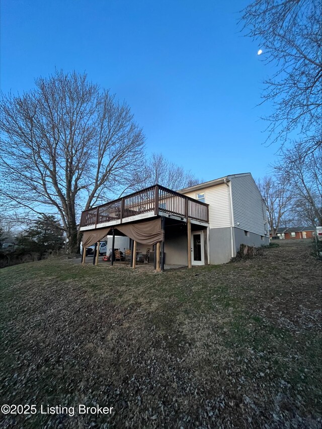 back of house featuring a deck and a lawn