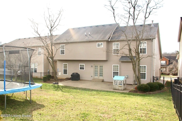 rear view of house featuring a trampoline, a patio area, a fenced backyard, and a lawn