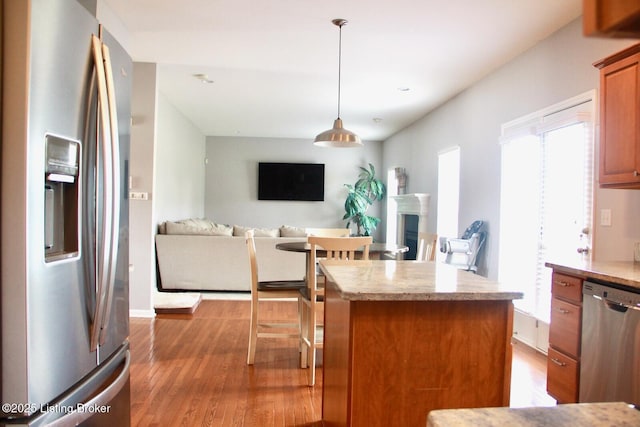 kitchen with a kitchen island, open floor plan, wood finished floors, light countertops, and stainless steel appliances