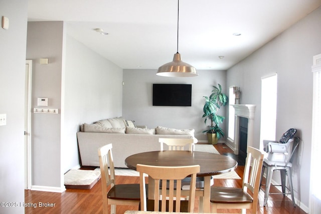 dining room featuring a fireplace, wood finished floors, and baseboards