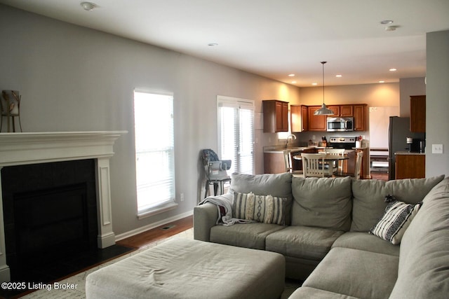 living room with recessed lighting, dark wood-style flooring, a fireplace, and baseboards