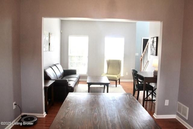living room featuring dark wood-style flooring, visible vents, baseboards, and stairs