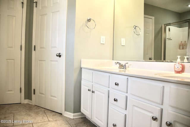 bathroom featuring tile patterned floors, a shower with shower door, a sink, and double vanity