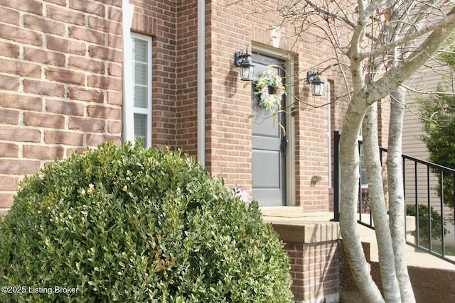 view of exterior entry with a garage and brick siding