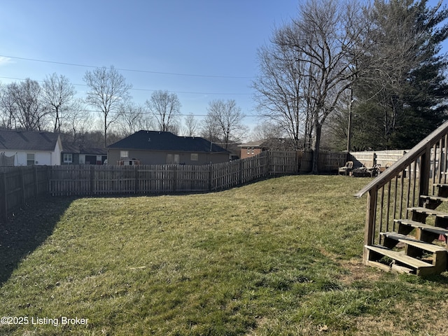 view of yard with a fenced backyard and stairway