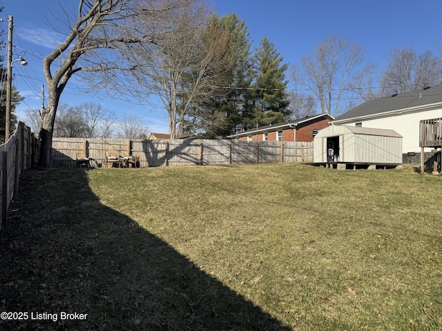 view of yard featuring a fenced backyard, a storage unit, and an outbuilding