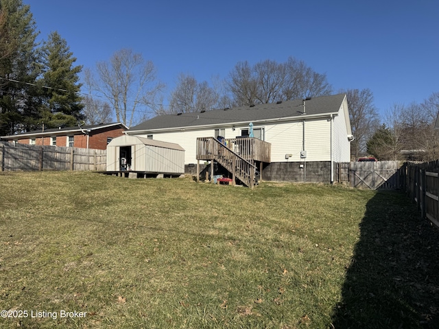 rear view of house with an outbuilding, a fenced backyard, a yard, stairway, and a storage unit