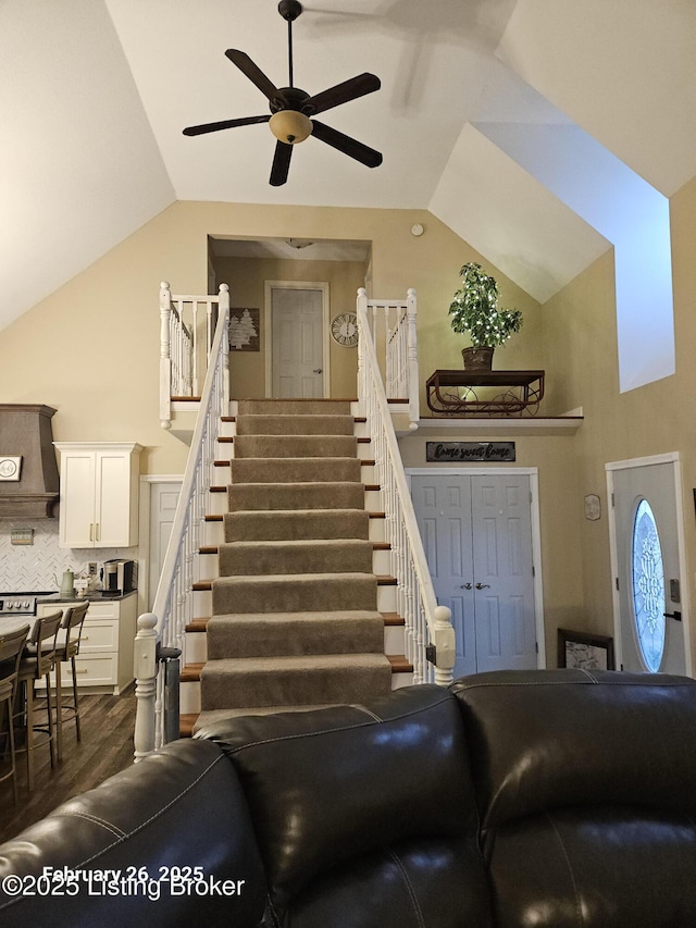 living area featuring dark wood-style floors, ceiling fan, stairway, and high vaulted ceiling