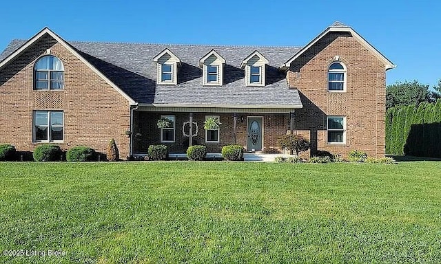 view of front facade with brick siding, a front yard, and a shingled roof