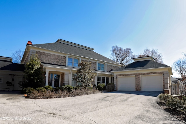 view of front facade with a garage, brick siding, and driveway