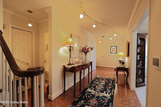 hall featuring tile patterned flooring, track lighting, baseboards, and ornamental molding