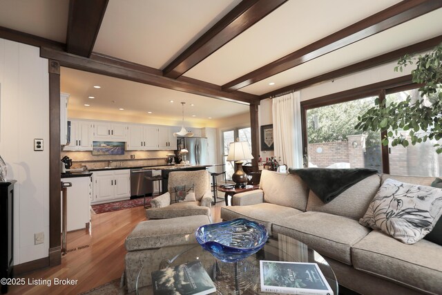 living room with dark wood finished floors, beamed ceiling, and recessed lighting