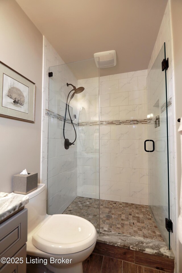 full bath with a stall shower, toilet, and vanity