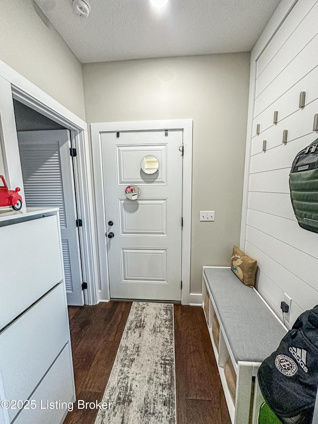 mudroom featuring wood walls, dark wood finished floors, and a textured ceiling