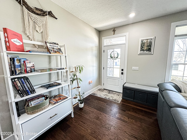 foyer entrance with a textured ceiling, wood finished floors, and baseboards